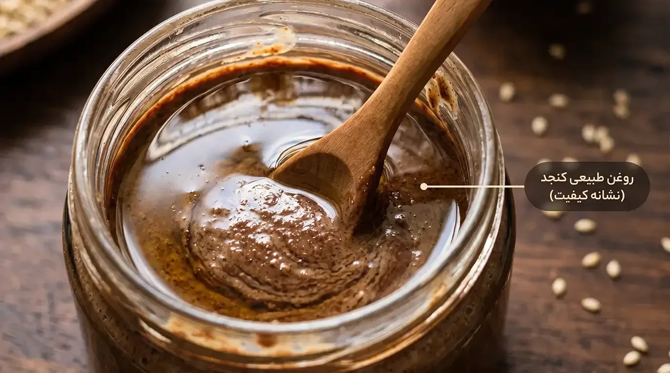 نمای نزدیک از روغن طبیعی جمع شده روی سطح ارده شکلاتی و هم زدن آن با قاشق چوبی